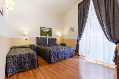 a bedroom with two beds and a large window at Hotel Paris in Rome