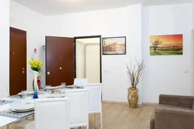 a white dining room with a table and chairs at House Gregorio in Rome