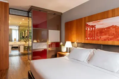 a bedroom with a large white bed and a bathroom at H10 Roma Città in Rome