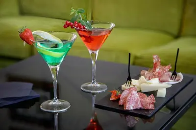 two cocktails on a table with a tray of food at Grand Hotel Fleming by OMNIA hotels in Rome