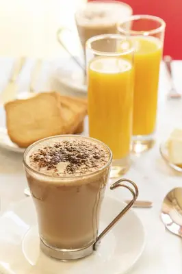 a cup of coffee on a plate with two glasses of orange juice at Hotel Tuscolana in Rome