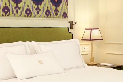 a white bed with a green headboard and a lamp at Palazzo Ripetta in Rome