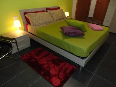 a bedroom with a green bed with pillows and a rug at Studiohouserome in Rome
