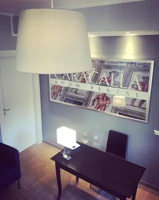 a desk with a lamp and a picture on a wall at Caracalla Room Rental in Rome