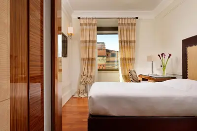 a bedroom with a bed and a desk and a window at UNA Hotels Decò Roma in Rome