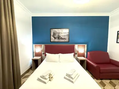 a bedroom with a bed and a red chair at The Five Oscars Inn in Rome