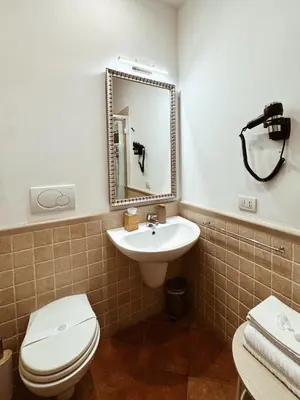 a bathroom with a sink and a toilet and a mirror at Residenza Sciarra Suites in Rome