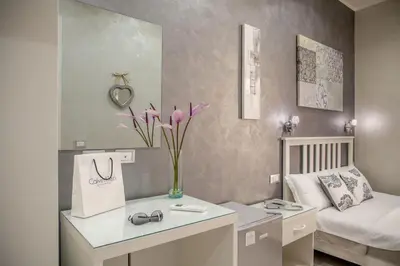 a room with a bed and a vase with purple flowers at Frattina Grand Suite Guesthouse in Rome