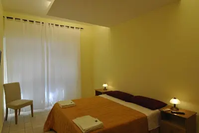 a bedroom with a bed and a chair and a window at Roma Tourist House in Rome
