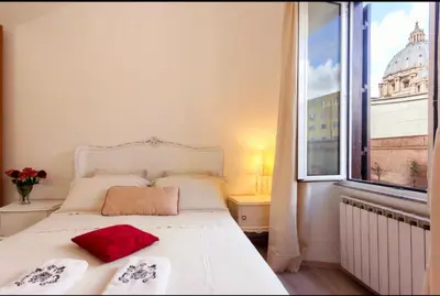 a bedroom with a white bed and a large window at Vatican View Apartment in Rome