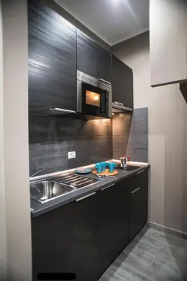 a black kitchen with a sink and a microwave at Costantino Secondo Guest House in Rome