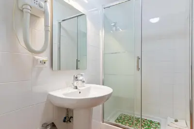 a white bathroom with a sink and a shower at Roma Enrico Guesthouse in Rome