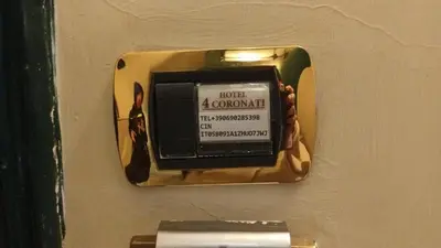 a soap dispenser on a wall with a sign on it at Hotel 4 Coronati in Rome