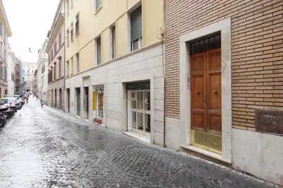 a wet street with a building and a brown door at Vatican Attic With Terrace in Rome