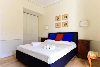 a bedroom with a large bed with blue and red pillows at Bright and Comfy 3 bedroom apt in Monti in Rome