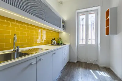 a kitchen with white cabinets and a sink and yellow tiles at Casa Vacanza 