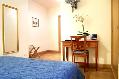 a bedroom with a desk and a bed with a blue bedspread at Domus Cavour Guest house in Rome