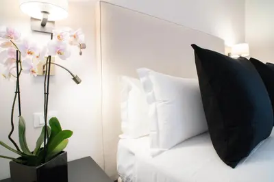 a white bed with a black pillow and a plant at Kame Hall in Rome
