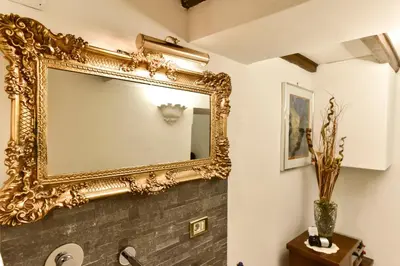 an ornate gold mirror on a wall above a bathroom sink at Loft Pantheon in Rome