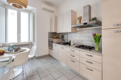 a kitchen with white cabinets and a table and a dining room at NOH Family Nest in Rome