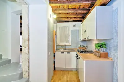 a kitchen with white cabinets and a wooden floor at Parione Charme - My Extra Home in Rome