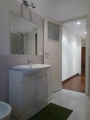 a white bathroom with a sink and a mirror at La Casa di Nonna Betta in Rome