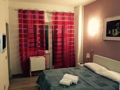 a bedroom with red curtains and a bed with two towels at Affittacamere Roma Tiburtina in Rome