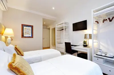 a hotel room with two beds and a desk at Vatican Chic B&B in Rome