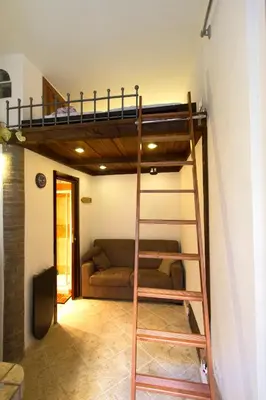 a loft bed in a living room with a couch at Underground Rome's Room in Rome