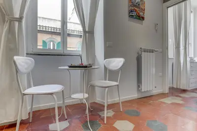 a kitchen with white stools and a table and a window at Appartamento Santi Quattro - Colosseo in Rome