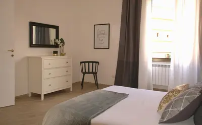 a bedroom with a bed and a dresser and a chair at Domus in Laterano in Rome
