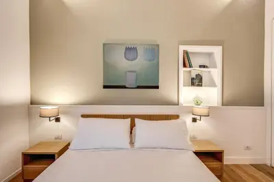 a bedroom with a bed with two lamps and a painting at Dopodomani Suite in Rome