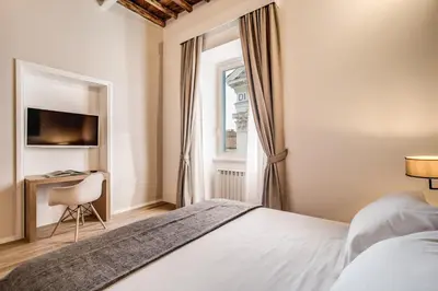 a bedroom with a bed and a window and a desk at Dopodomani Suite in Rome
