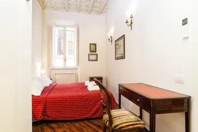 a bedroom with a red bed and a desk and a window at Vicolo Torretta - FromHometoRome in Rome