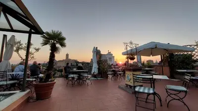 a rooftop patio with tables and chairs and a sunset at Residenza Maritti Classic Rooms - Guesthouse in Rome