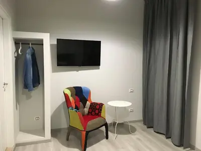 a room with a chair and a tv on a wall at CinqueSogni Guest House in Rome