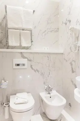 a white bathroom with a toilet and a sink at Margherita Suites in Rome