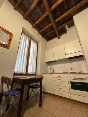 a kitchen with white cabinets and a table and a window at Navona Apartment Livia in Rome