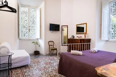 a bedroom with two beds and a table and a mirror at B&B Domus Aurea in Rome