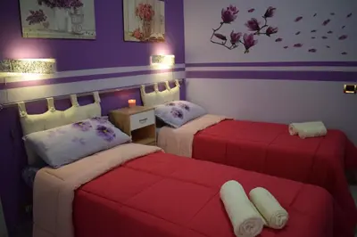 two beds in a room with purple and purple walls at I Petali Guest House in Rome