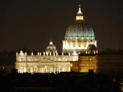 a lit up domed building at night at Vatican City House Roma in Rome