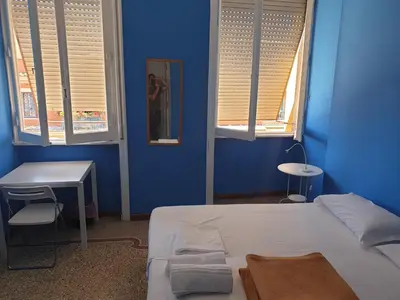 a blue room with a bed and two windows at Art in Accommodation in Rome