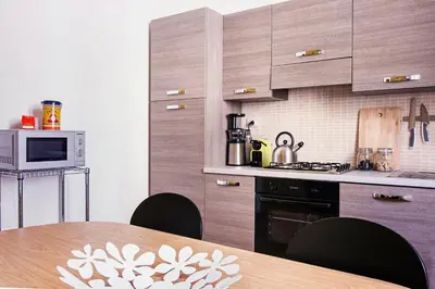 a kitchen with wooden cabinets and a table with chairs at TrastevereHome - Peretti Rome in Rome