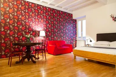 a bedroom with a bed and a red chair at TrastevereHome - Paglia House of 17Century in Trastevere in Rome
