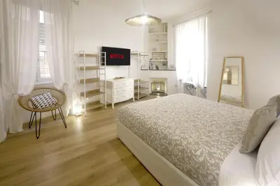 a white bedroom with a bed and a television at Buongiorno Colosseo in Rome