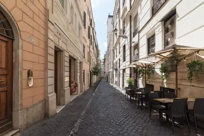 an empty street with tables and chairs in an alley at Casa Zeffiro - FromHometoRome in Rome