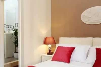 a bedroom with a white bed with red pillows at Liberty Rome Apartment - Liberty Collection in Rome