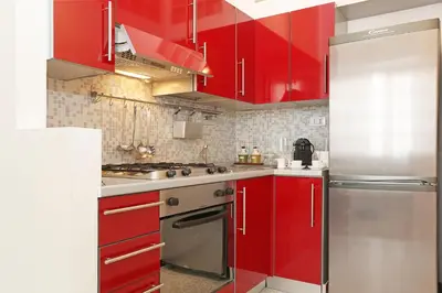 a kitchen with red cabinets and a stainless steel refrigerator at Liberty Rome Apartment - Liberty Collection in Rome