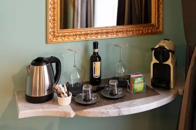 a shelf with a bottle of wine and two glasses at Le Suite del Barone in Rome