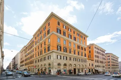 a tall orange building on a city street with cars at Domus Mari in Rome
